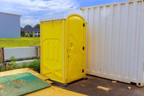 Jobsite porta potty rental beside construction equipment in Newark and North Jersey